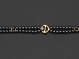 un bracelet en perles noires avec un fermoir doré sur fond noir