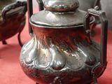 trois théières en argent posées sur une nappe rouge