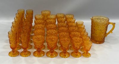 a lot of orange glass cups and pitchers on the table