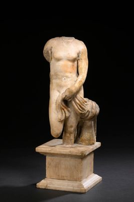 une statue antique représentant un homme tenant un bouclier, posée sur un socle