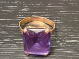 an image of a purple stone ring sitting on top of a wooden table