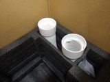 two white toilets in the corner of a bathroom