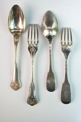 five silver spoons and two silver spoons on a white surface