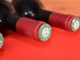 three bottles of wine sit on a red cloth on a table