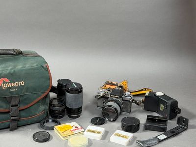 un appareil photo, un étui pour appareil photo, un objectif, un étui pour appareil photo et d'autres objets disposés sur une table