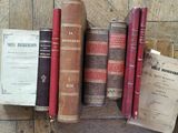 several old books are lined up on a shelf on a wooden floor