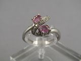un gros plan d'une bague sertie d'un saphir rose et de diamants, posée sur un socle transparent