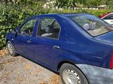 une voiture bleue garée sur un parking, à côté d'un buisson