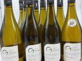 six bouteilles de vin blanc sont alignées sur un comptoir