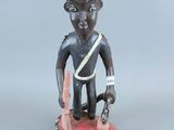 figurine représentant un homme tenant un couteau dans une main et un autre couteau dans l'autre