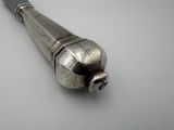 a silver object on a white surface with a black handle