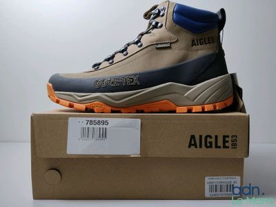 des chaussures de randonnée pour homme dans une boîte posée sur une surface blanche