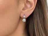 La femme porte une paire de boucles d'oreilles et un pull blanc.