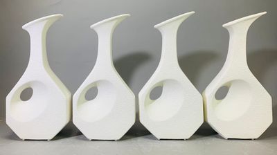 quatre vases blancs sont alignés sur une table