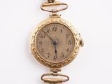 une montre en or entourée d'une chaîne sur une surface blanche