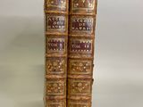 two old books are sitting on a white surface with a white background