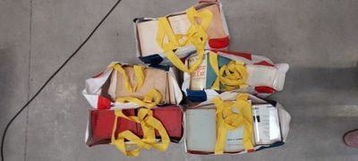 une pile de livres entourée d'un ruban jaune, posée par terre