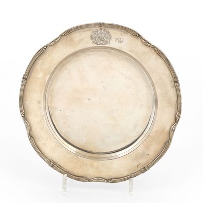 une assiette en argent posée sur un socle, avec un motif sur le bord