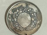 a silver plate with a wreath on it on a table