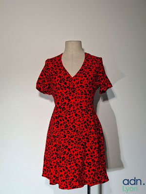 La robe est rouge et noire, avec des taches noires.