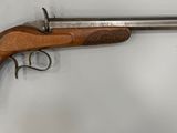 un vieux pistolet accroché au mur, muni d'une crosse en bois
