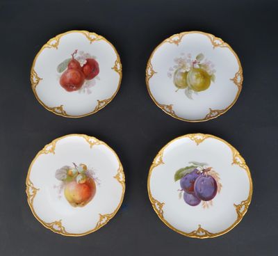 four plates with fruit painted on them sitting on a table