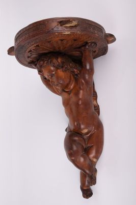 une sculpture ancienne en bois représentant un enfant tenant un bol sur la tête