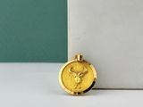 un collier en or orné d'une pièce d'or, posé sur une surface blanche