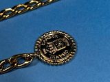 a gold chain with a medallion on it on a blue surface