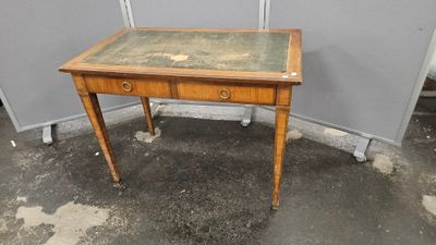 une vieille table en bois avec un plateau en verre, posée sur un sol en béton