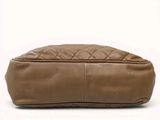 the large tan leather bag is sitting on a white surface