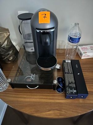a coffee maker on a table with water bottles and other items