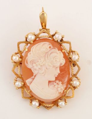 un gros plan sur un pendentif camée en or et corail orné de perles