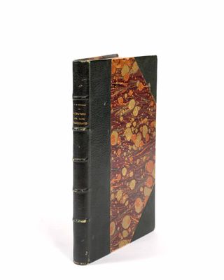 un vieux livre à la couverture noire posé sur une surface blanche