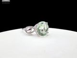 a close up of a ring with a green diamond on top of a white plate