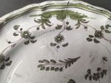 a green and white plate with flowers and leaves on it