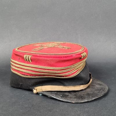 un vieux chapeau rouge orné d'un bandeau en cuir et d'une lanière marron
