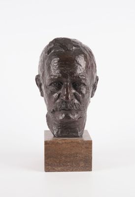 un gros plan d'un buste d'homme en bronze posé sur un socle en bois