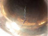 a silver bell with a crack in the middle of it