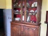 a wooden china cabinet in the corner of the room
