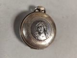 an image of a silver pocket watch with a picture of a man on it