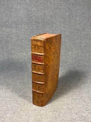 an old book is sitting on a table with a gray background