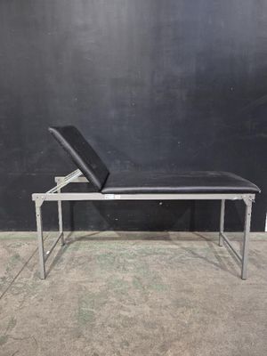 un banc noir sur lequel est posé un ordinateur portable, devant un mur noir