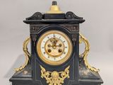 une horloge noire et or posée sur une surface blanche