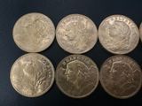 six different types of silver coins on a black surface