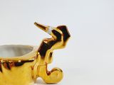a gold cup with a horse on it on a white surface