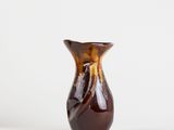 a brown vase sitting on top of a table next to a white wall