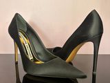 black high heeled shoes on a black table with a pink wall in the background