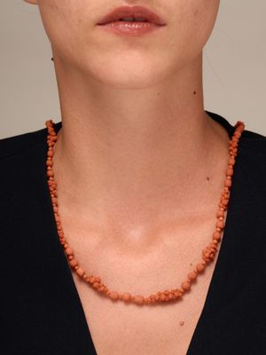 une photo d'une femme portant un collier composé de perles orange