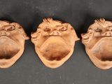 trois têtes de singes sculptées sur un fond noir